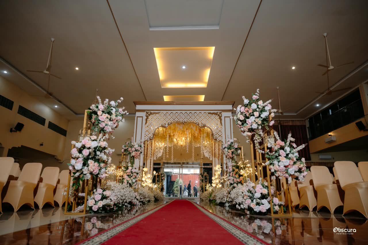 Dekorasi lorong akad dengan kain draping, bunga, dan karpet merah
